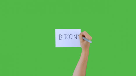 Frau-Schreibt-Bitcoin-Auf-Papier-Mit-Grünem-Bildschirm